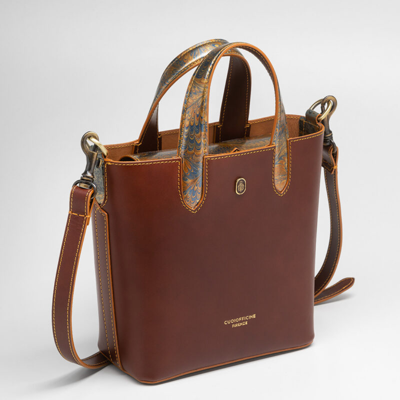 Italian vegetable tanned mini shopping bag leather from one of the most historic Tuscany tannery with light camel patent interior. Handcrafted marbeled details on the handles and the closure flap. Papaya